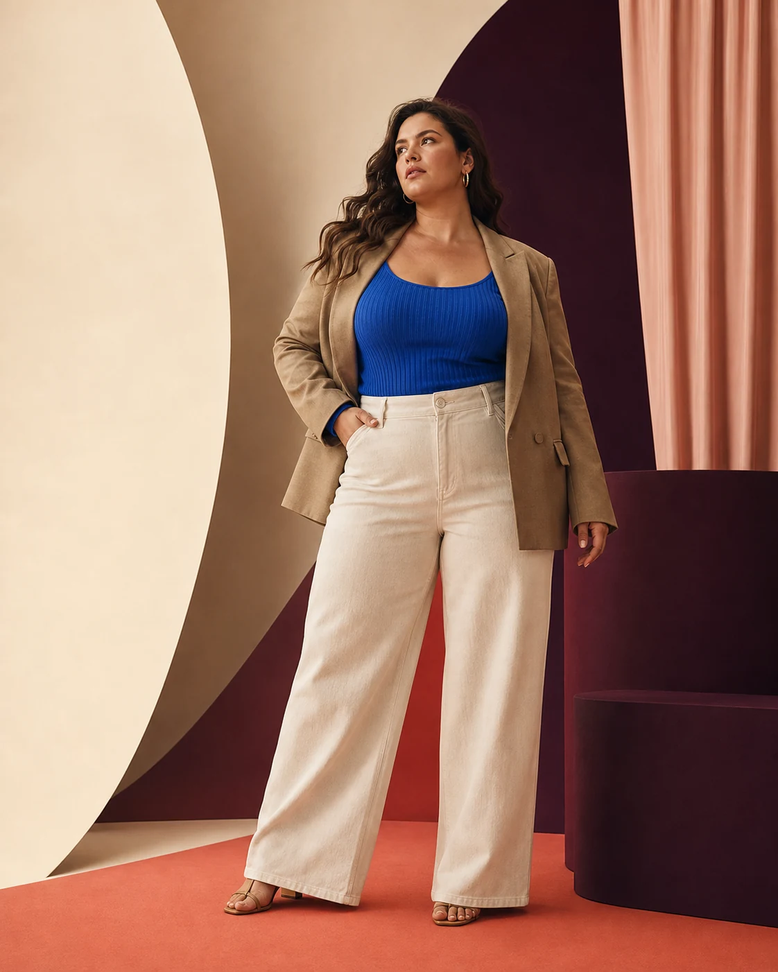 Modella plus-size con blazer sartoriale, top blu e pantaloni crema