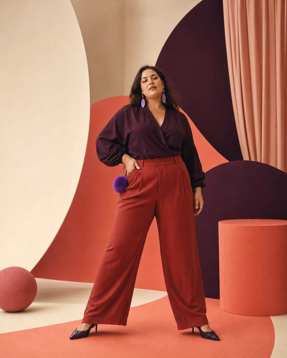 Modella plus-size in camicia prugna e pantaloni corallo in un set geometrico