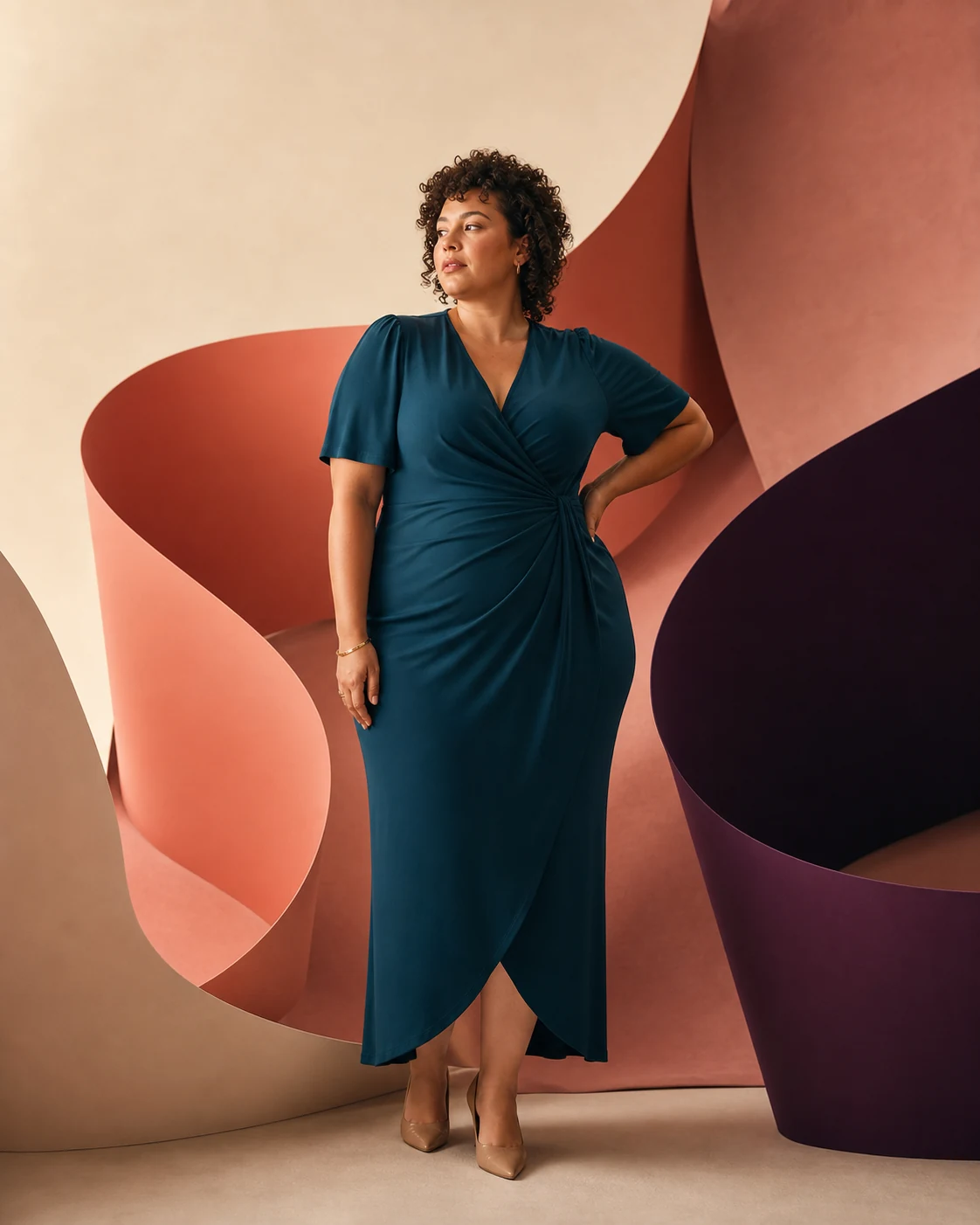 Modella plus-size con abito teal tra forme scultoree curve