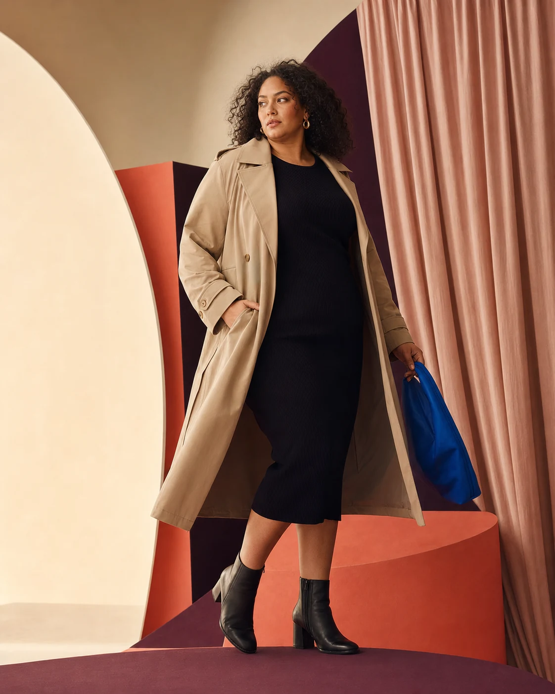 Modella plus-size con abito nero e trench chiaro