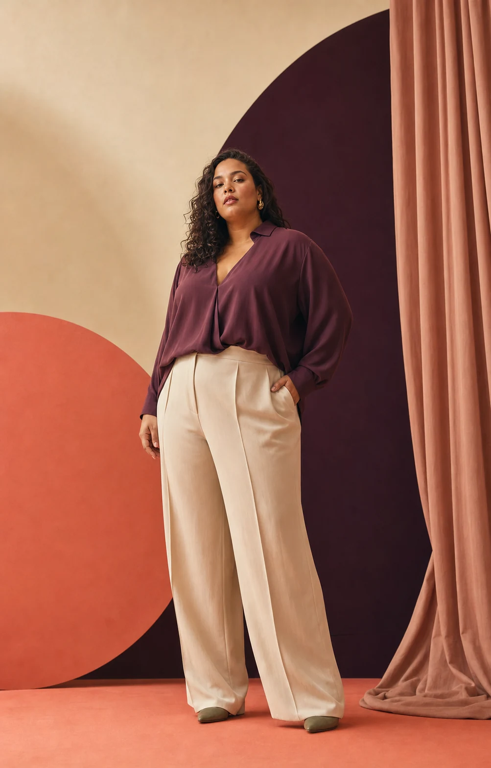 Modella plus-size con blusa prugna e pantaloni crema